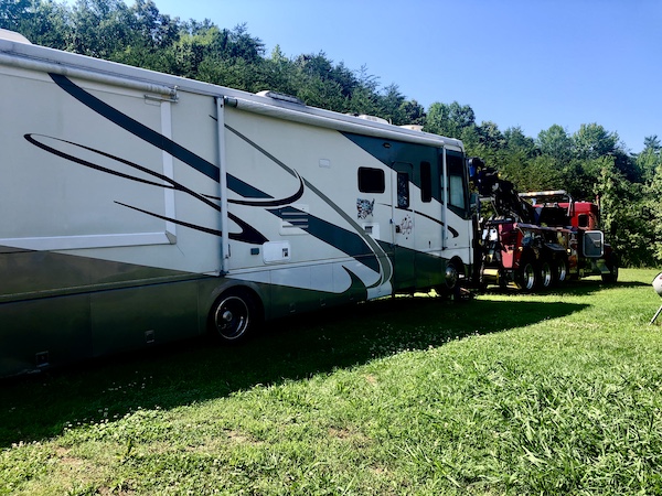 Red tow truck towing our motorhome from behind our son's home.
