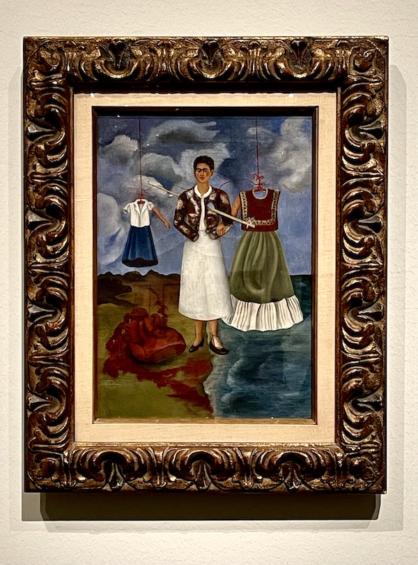 Painting of a woman with 2 dress the spear to be floating at the Frida Kahlo Exhibit Houston