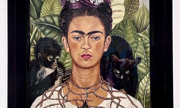 Painting of Frida with small monkey, thorn necklace, black cat and hummingbird on display at the Frida Kahlo Exhibit Houston