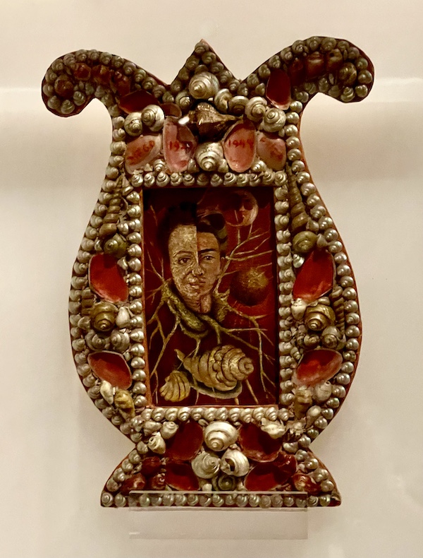 Painting of Frida and her husband Diego Rivera in a frame that's shaped like a lyre decorated with shells