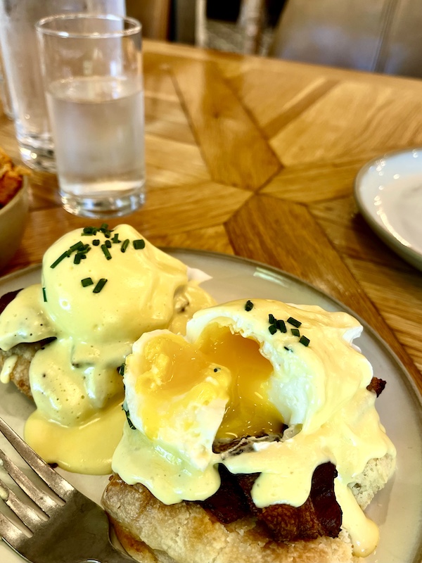 Poached eggs with yolk dripping out down the side of the biscuit at Magnolia Table Waco Texas