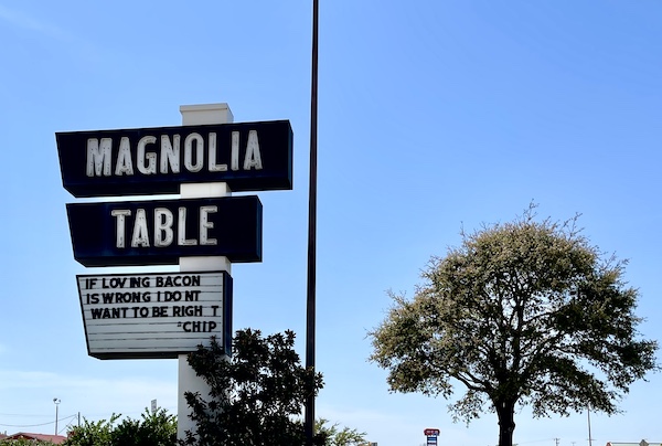 Large lit sign for Magnolia Table Waco Texas curbside of the parking lot.