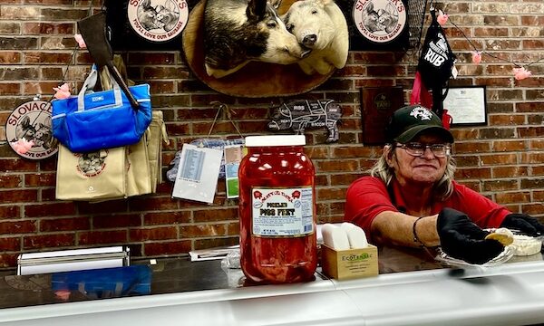 Woman behind a food counter serving a cracker with Jerky spread at Slovacek's in West Texas
