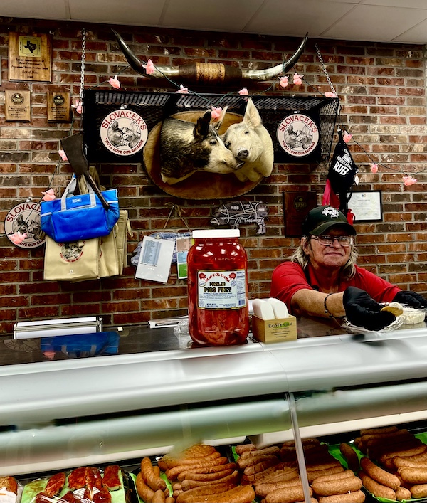 Woman behind a food counter serving a cracker with Jerky spread at Slovacek's in West Texas