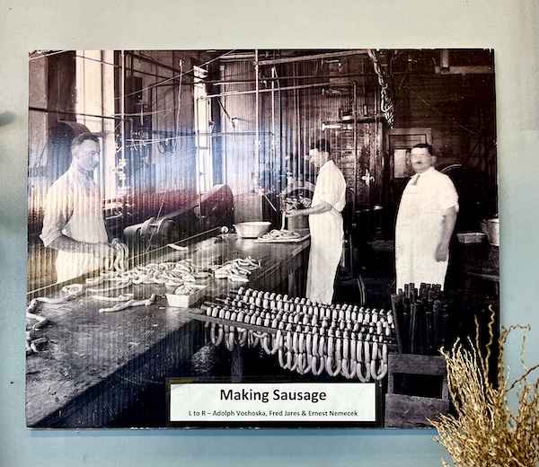 Old photo of three men making sausages and lots of sausages hanging at Slovacek's in West Texas