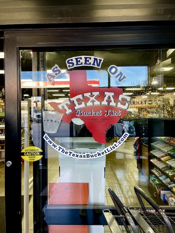 Decal of State of Texas in red with words As seen on Texas Bucket List on window of Slovacek's in West Texas