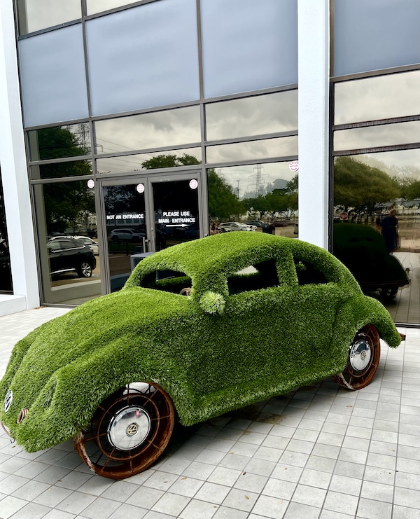 Volkswagen Beetle completely covered in plants in front of DFW Car and Toy Museum