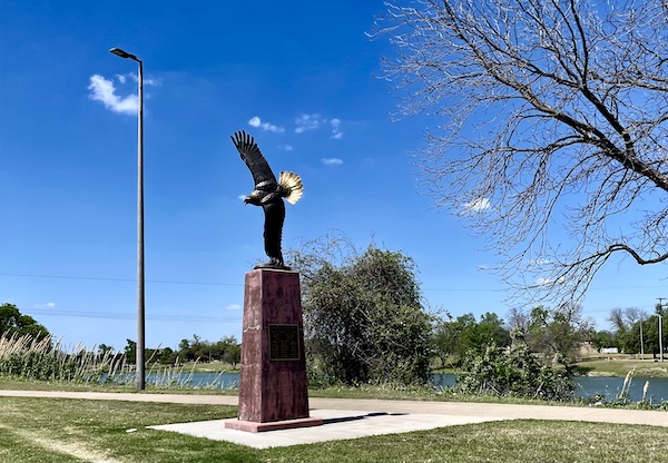 Sculpture of an eagle with wingtip attached to red stone pillar at Indian Springs Park Waco Texas