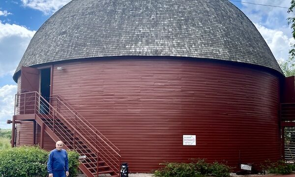 Round red barn with domed roof and blue sky with white puffy clouds is the Arcadia Round Barn Oklahoma