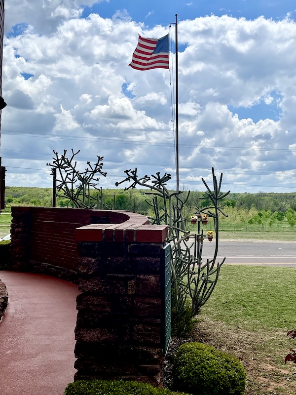 Wall, cacti, flowers and flag at entrance to Arcadia Round Barn Oklahoma
