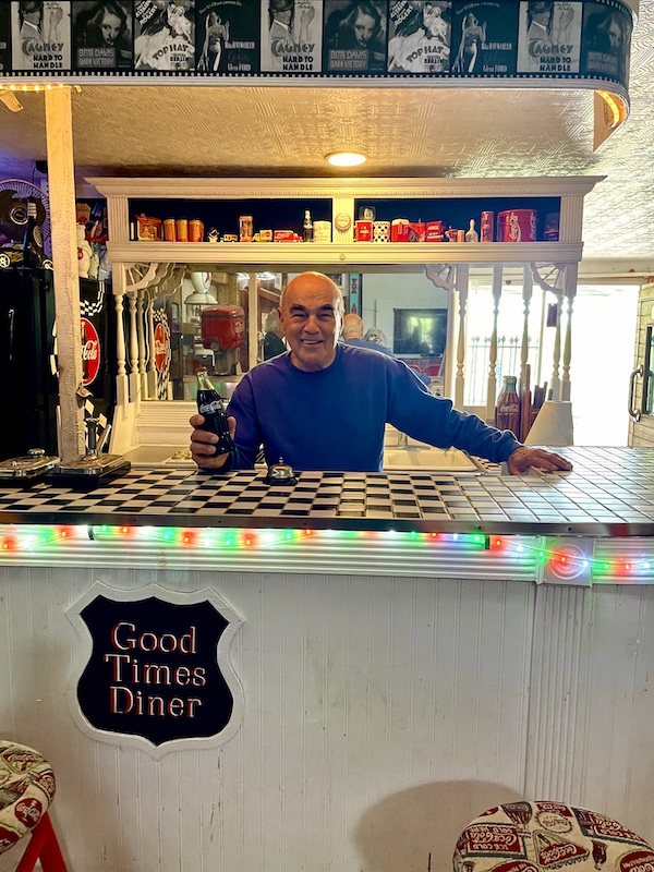 Steve behind the counter at a diner offering a bottle of Coke at John's Place Arcadia Oklahoma