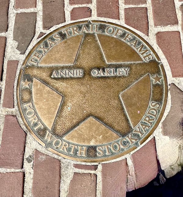 Bronze star embedded in the red brick paver sidewalk at The Stockyards Fort Worth Texas honoring Annie Oakley