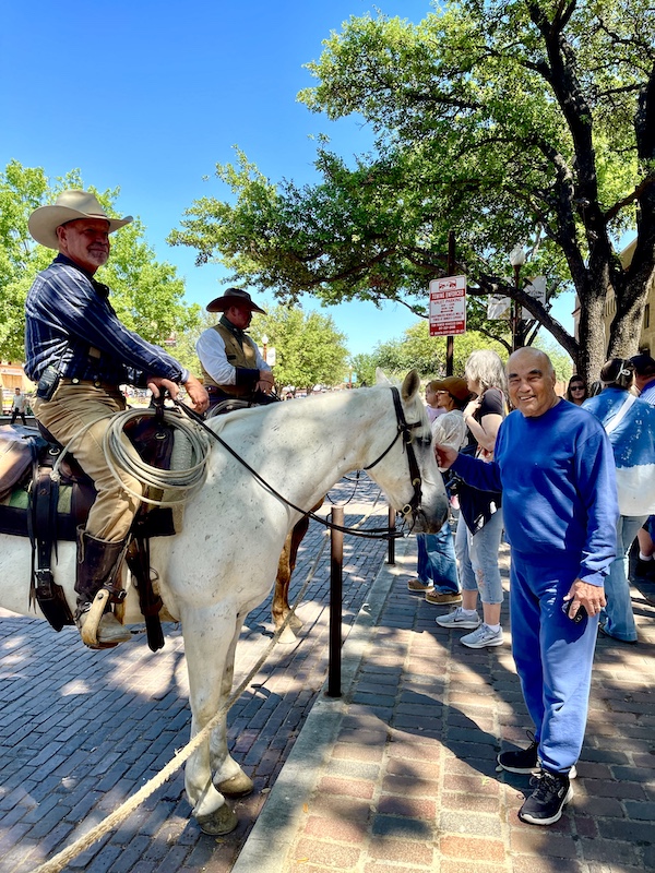 Steve in a blue sweatsuit petting a white horse at The Stockyards Fort Worth Texas