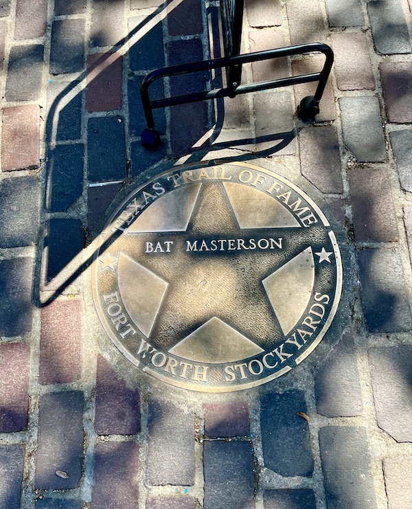 Bronze star embedded in the red brick paver sidewalk at The Stockyards Fort Worth Texas honoring Bat Masterson