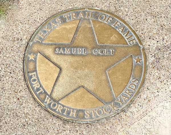 Bronze star embedded in the red brick paver sidewalk at The Stockyards Fort Worth Texas honoring Sam Colt