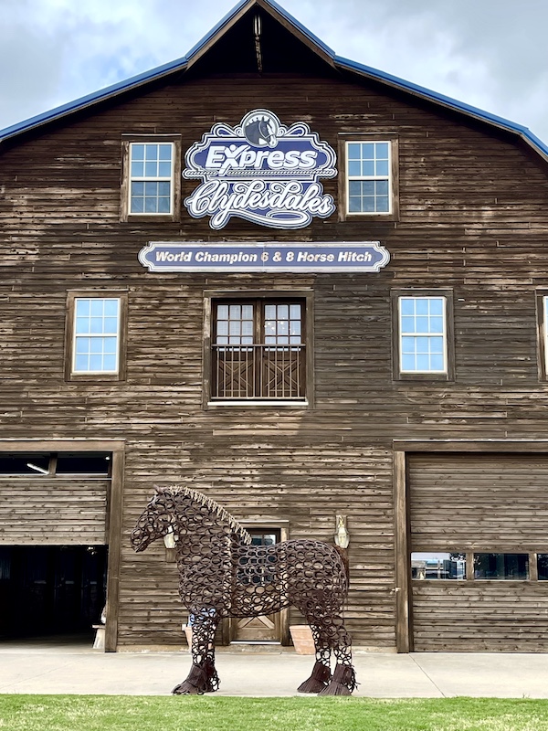 Large brown wood barn with horse sculpture in front is the home of Express Clydesdales Yukon Oklahoma