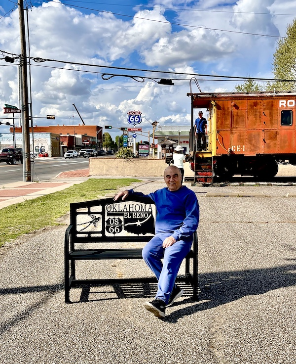 Happy 100 Route 66! Steve relaxing on a wrought iron park bench marked with its location.